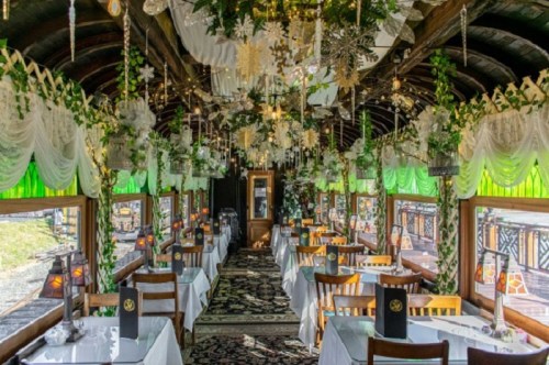 A beautifully decorated restaurant interior with green accents, floral arrangements, and elegant table settings.