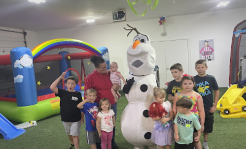 A group of children poses with a person in an Olaf costume in a colorful indoor play area.
