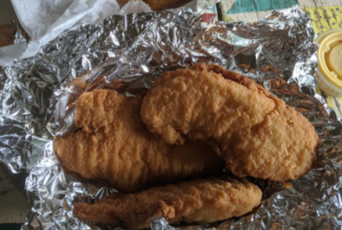 Three pieces of golden-brown fried chicken tenders on crinkled aluminum foil.
