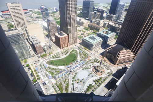 Aerial view of a cityscape featuring buildings, parks, and streets bustling with activity.