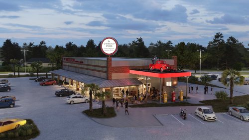 A modern restaurant with a red roof and vintage car on top, surrounded by a parking lot and trees under a cloudy sky.