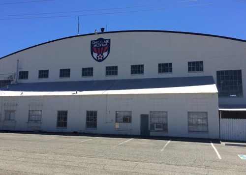 Exterior of the Chico Air Museum, featuring a large sign and a clear blue sky above.