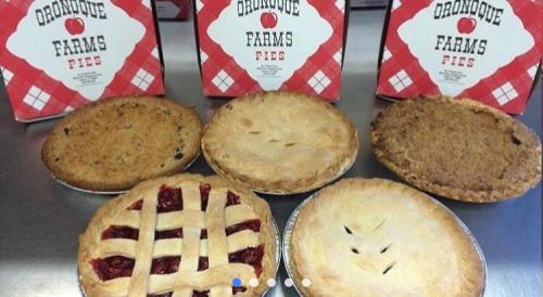 A variety of pies displayed on a table, with two boxes of Oronque Farms Pies in the background.