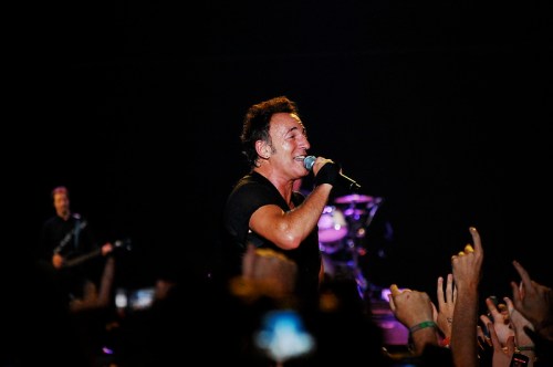 A singer performs on stage, engaging with the audience, while a guitarist plays in the background.