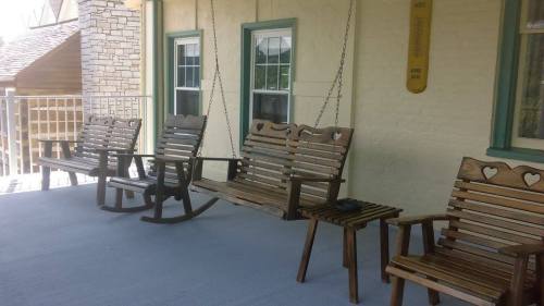 A porch with wooden rocking chairs and swings, featuring heart-shaped cutouts, against a light-colored wall.