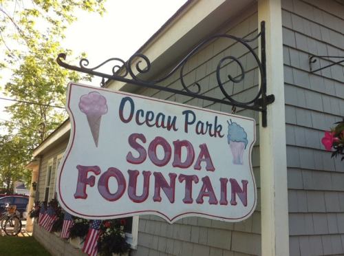 Sign for Ocean Park Soda Fountain featuring ice cream cones, hanging from a decorative bracket.