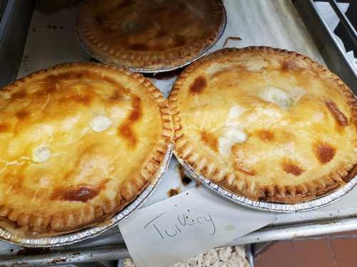 Two golden-brown turkey pies on a baking tray, with a handwritten label reading "Turkey" nearby.