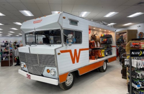 A vintage-style food truck inside a store, featuring shelves stocked with various tools and merchandise.