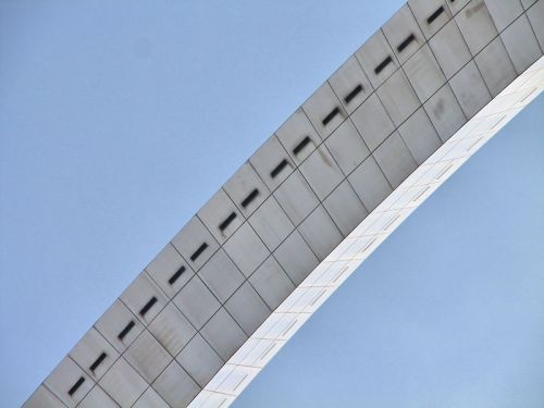 A curved architectural structure reflecting a clear blue sky.