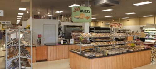 A bakery display with various baked goods and a sign reading "Lil's Bakery" in a grocery store setting.