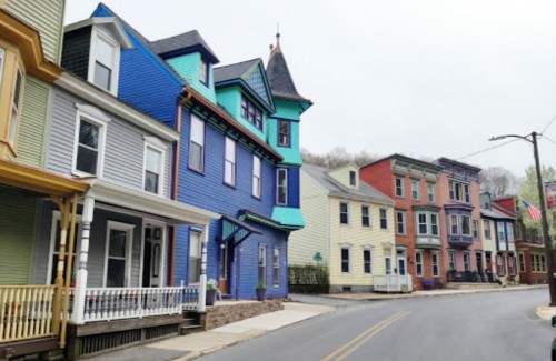 Colorful Victorian-style houses line a quiet street, showcasing vibrant hues of blue, green, and yellow.