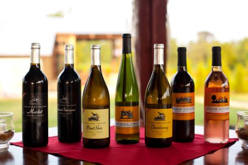A selection of wine bottles on a table, featuring various types like Merlot, Pinot Grigio, and Chardonnay.
