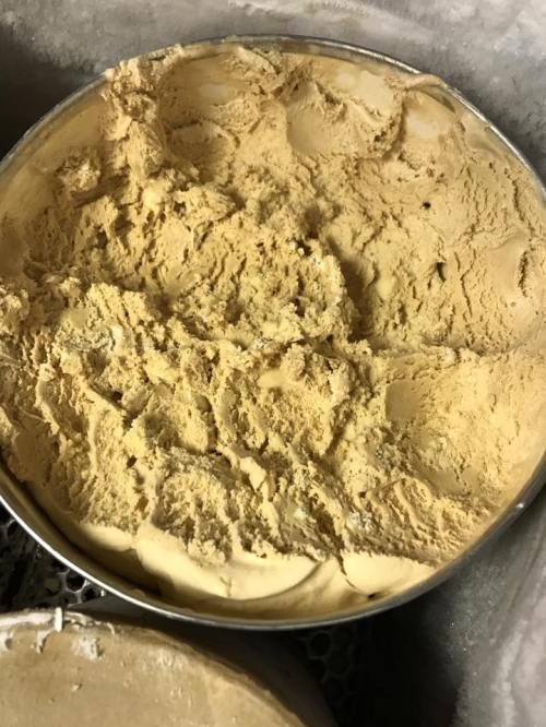 A round container filled with creamy, light brown ice cream, showing a textured surface.