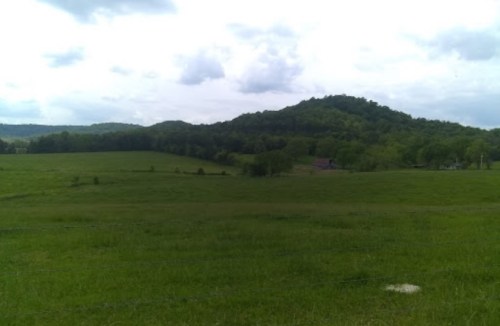 A lush green landscape with rolling hills under a cloudy sky.