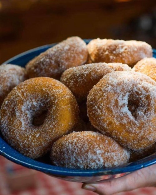 A blue bowl filled with freshly made, sugar-coated donuts.