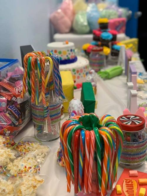 A colorful display of various candies, including candy canes, popcorn, and cotton candy, arranged on a table.