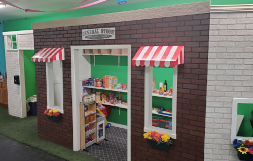 A colorful play area featuring a mock general store with shelves of food items and decorative awnings.