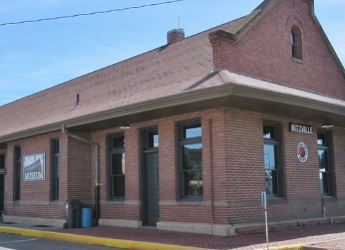 Historic brick building with large windows, labeled as the Ritzville Museum, set against a clear blue sky.