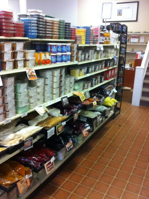 A well-organized store aisle filled with various containers of spices, sauces, and dry goods on shelves.