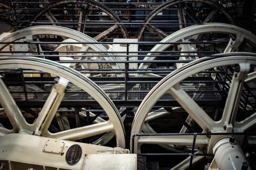 Close-up of large industrial wheels and machinery in a factory setting, showcasing intricate mechanical design.