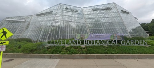 Exterior view of the Cleveland Botanical Garden featuring a modern glass structure and lush greenery.