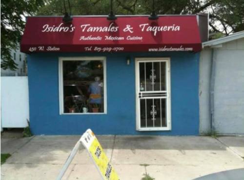 A blue building with a red awning that reads "Isidro's Tamales & Taqueria" and a sign for authentic Mexican cuisine.