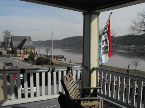 View from a porch overlooking a river, with a flag and a wooden chair in the foreground, and hills in the background.
