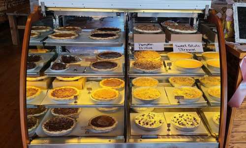 A display case filled with various pies, including pumpkin, pecan, and sweet potato, all beautifully arranged.