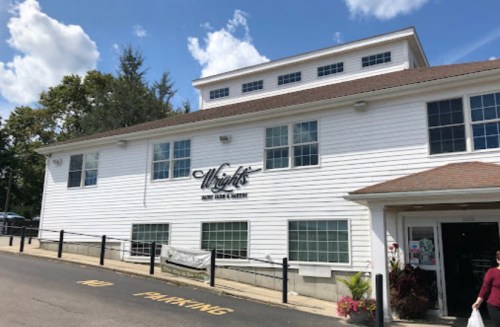 Exterior of Wright's Barn and Market, a white building with large windows and a sign, set against a blue sky.