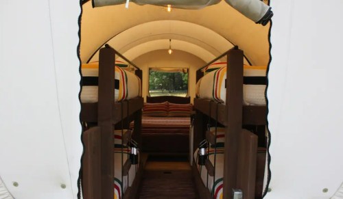 Interior view of a cozy glamping tent with bunk beds and warm lighting.
