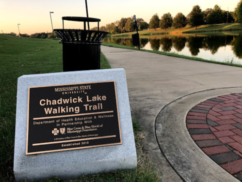 Sign for Chadwick Lake Walking Trail at Mississippi State University, with a scenic view of the lake and path nearby.