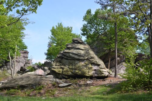 A rocky landscape with large boulders surrounded by green trees and clear blue skies.