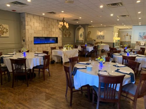 Elegant restaurant interior with round tables, blue lighting, and floral centerpieces, creating a warm atmosphere.