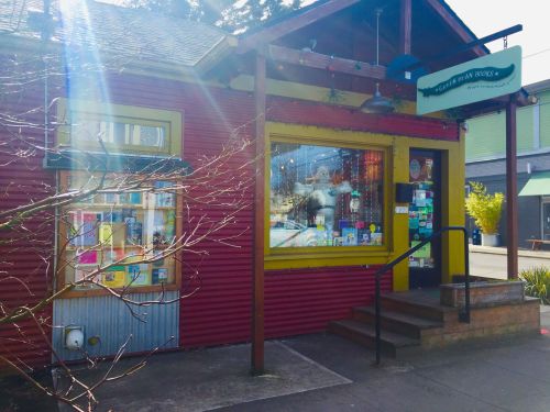 A colorful, red storefront with a green sign, featuring large windows and a welcoming entrance.