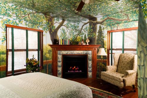 Cozy bedroom with a nature-themed mural, a stone fireplace, and a comfortable armchair by the window.