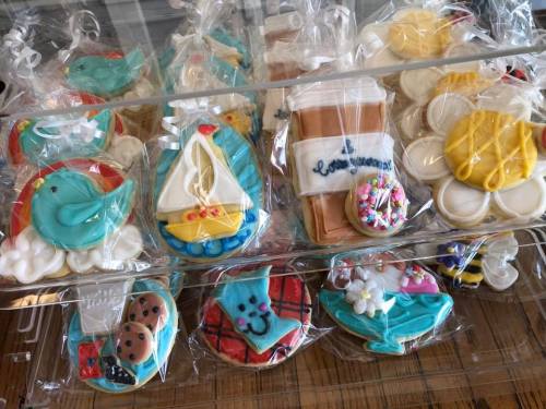 A variety of decorated cookies in clear bags, featuring designs like birds, boats, and flowers.