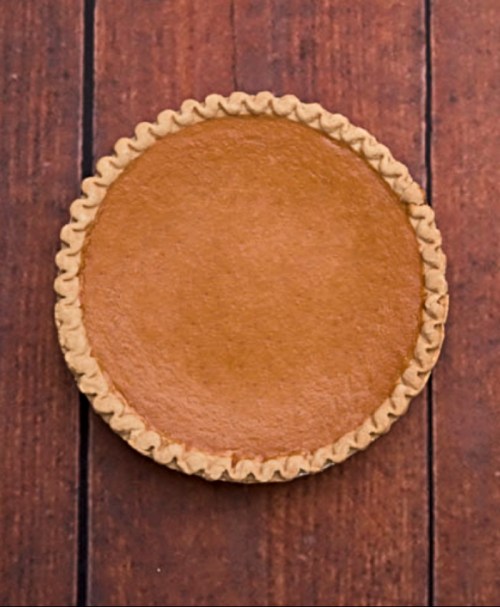 A round pumpkin pie with a golden crust, placed on a wooden surface.