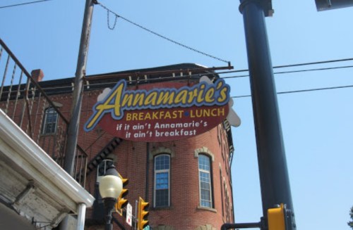 Sign for Annamarie's Breakfast Lunch, featuring a playful slogan about breakfast. Bright blue sky in the background.