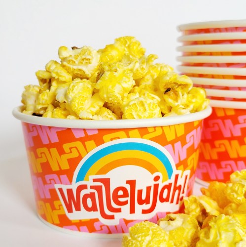 A colorful cup filled with buttery popcorn, with additional empty cups stacked in the background.