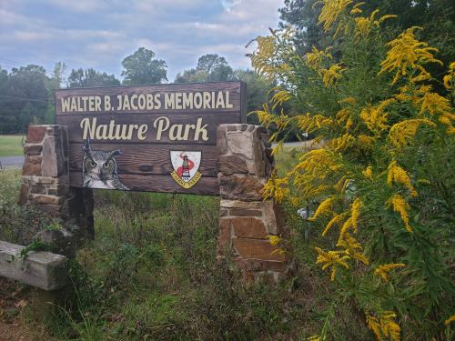 Sign for Walter B. Jacobs Memorial Nature Park, surrounded by greenery and wildflowers.