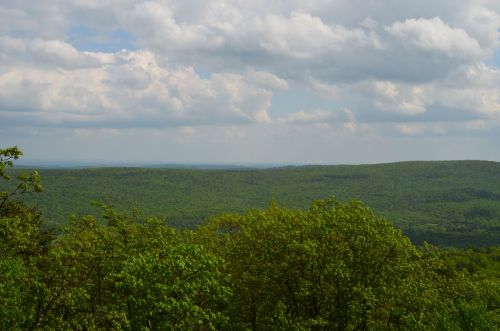 A panoramic view of lush green hills under a cloudy sky, showcasing a serene natural landscape.
