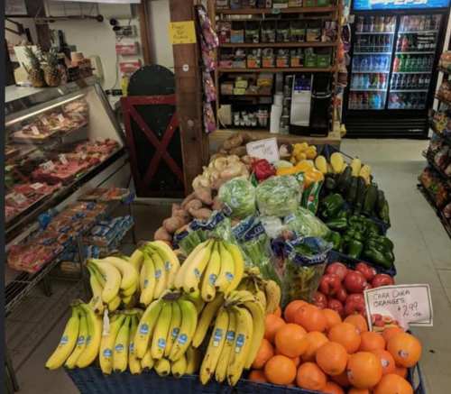 A vibrant display of fresh fruits and vegetables in a grocery store, including bananas, oranges, and various greens.