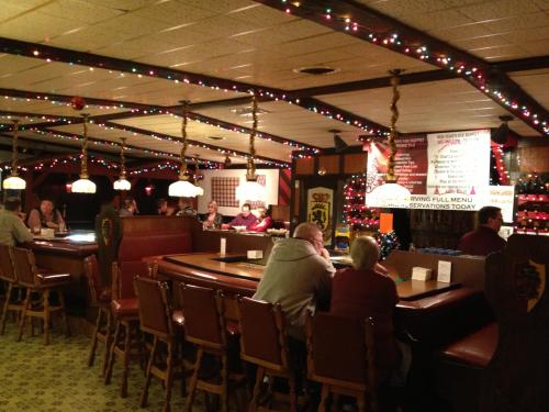 A cozy restaurant interior decorated with colorful lights, featuring patrons seated at tables and a bar area.