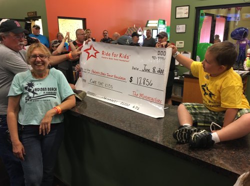 A group celebrates as a large check for $17,856 is presented to the Ride for Kids foundation.