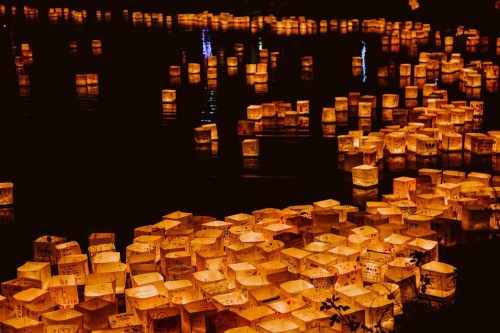 A serene scene of glowing lanterns floating on dark water, creating a warm, enchanting atmosphere.