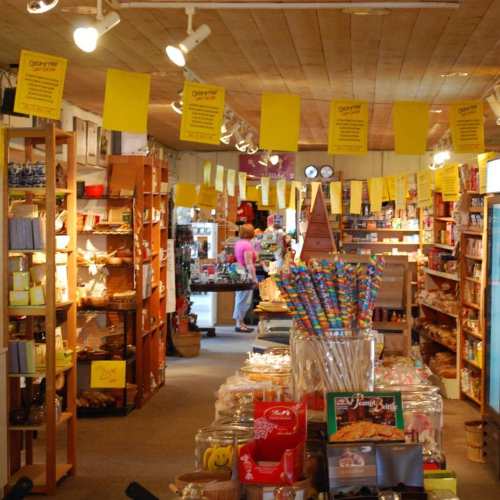 A colorful store aisle filled with shelves of various products, decorated with yellow sale signs and candy displays.