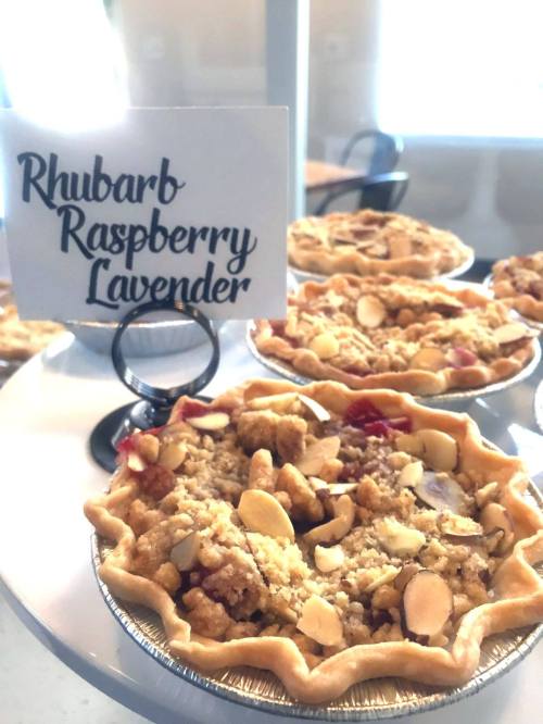 A close-up of mini pies with a sign reading "Rhubarb Raspberry Lavender" and topped with sliced almonds.