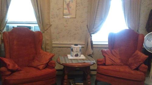 Cozy living room with two orange armchairs, a small table, and curtains by a window.