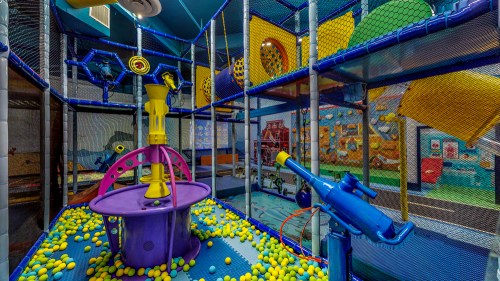 Colorful indoor play area with nets, ball pits, and interactive equipment for children.