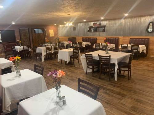 A cozy restaurant interior with neatly set tables, white tablecloths, and colorful flower centerpieces.